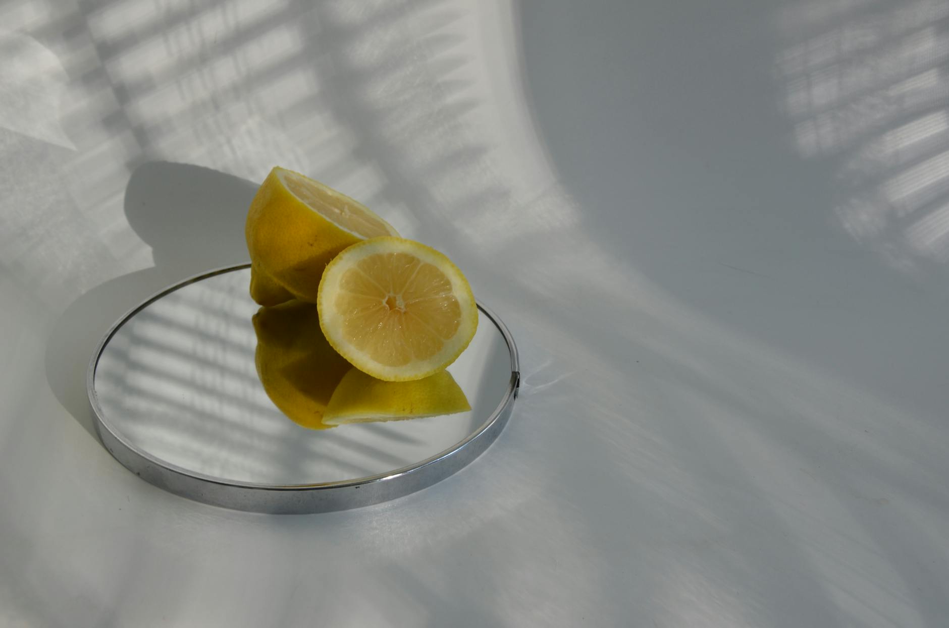 A hand holding a lemon on a soft pink background, surrounded by additional lemons