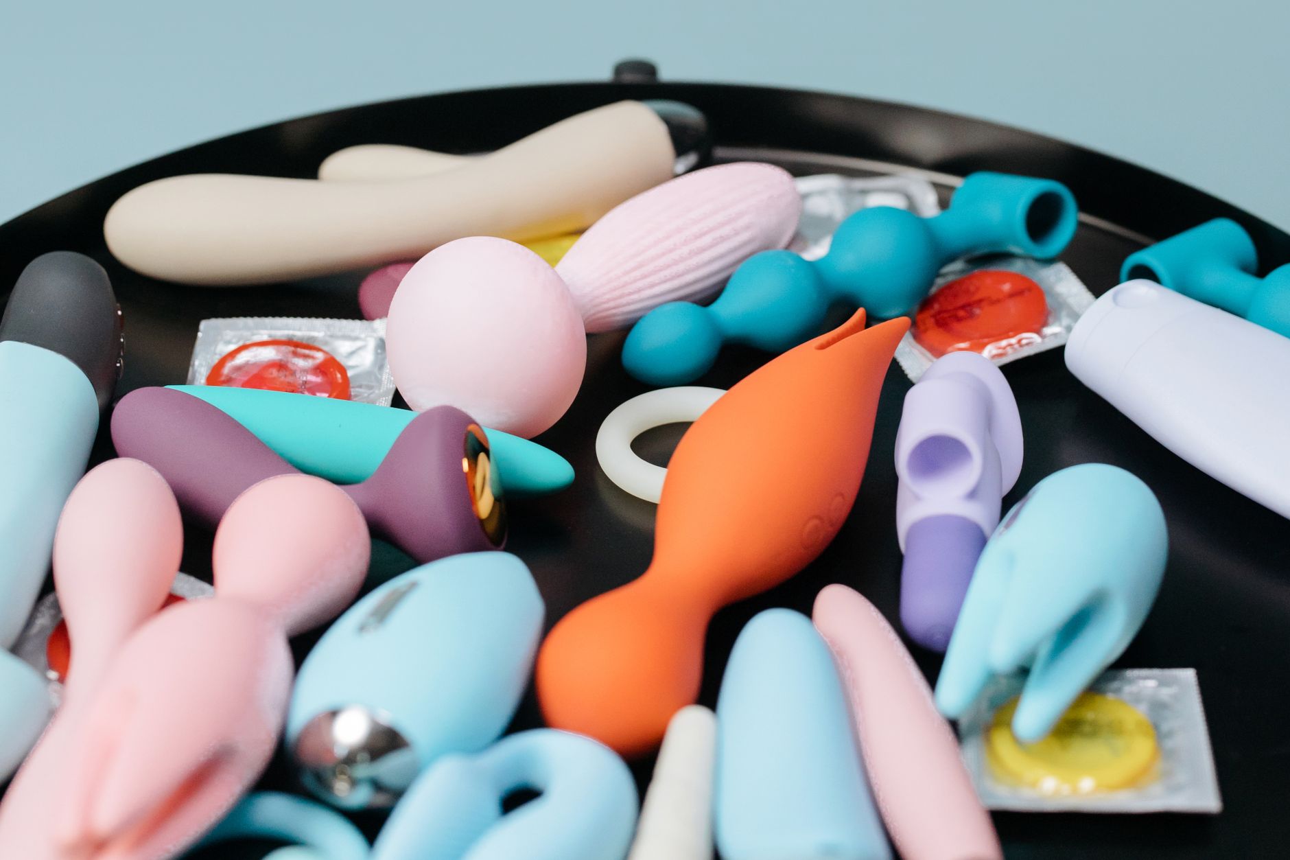 A curated collection of colorful vibrators and pleasure toys arranged on a black surface